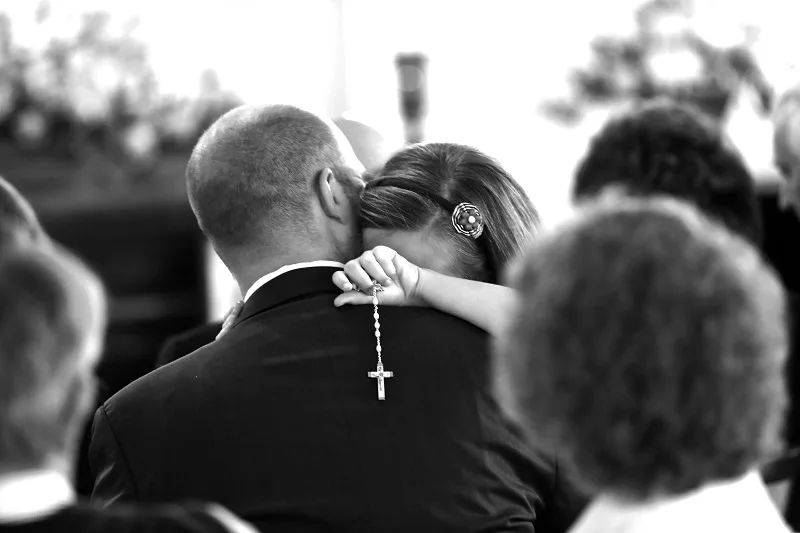 child with her father and a rosary bw