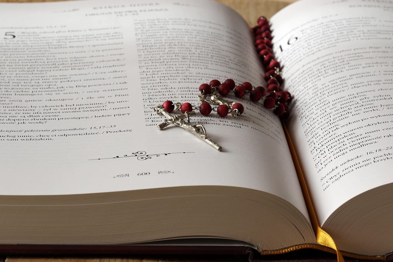A picture of a Rosary in the top of an open book.