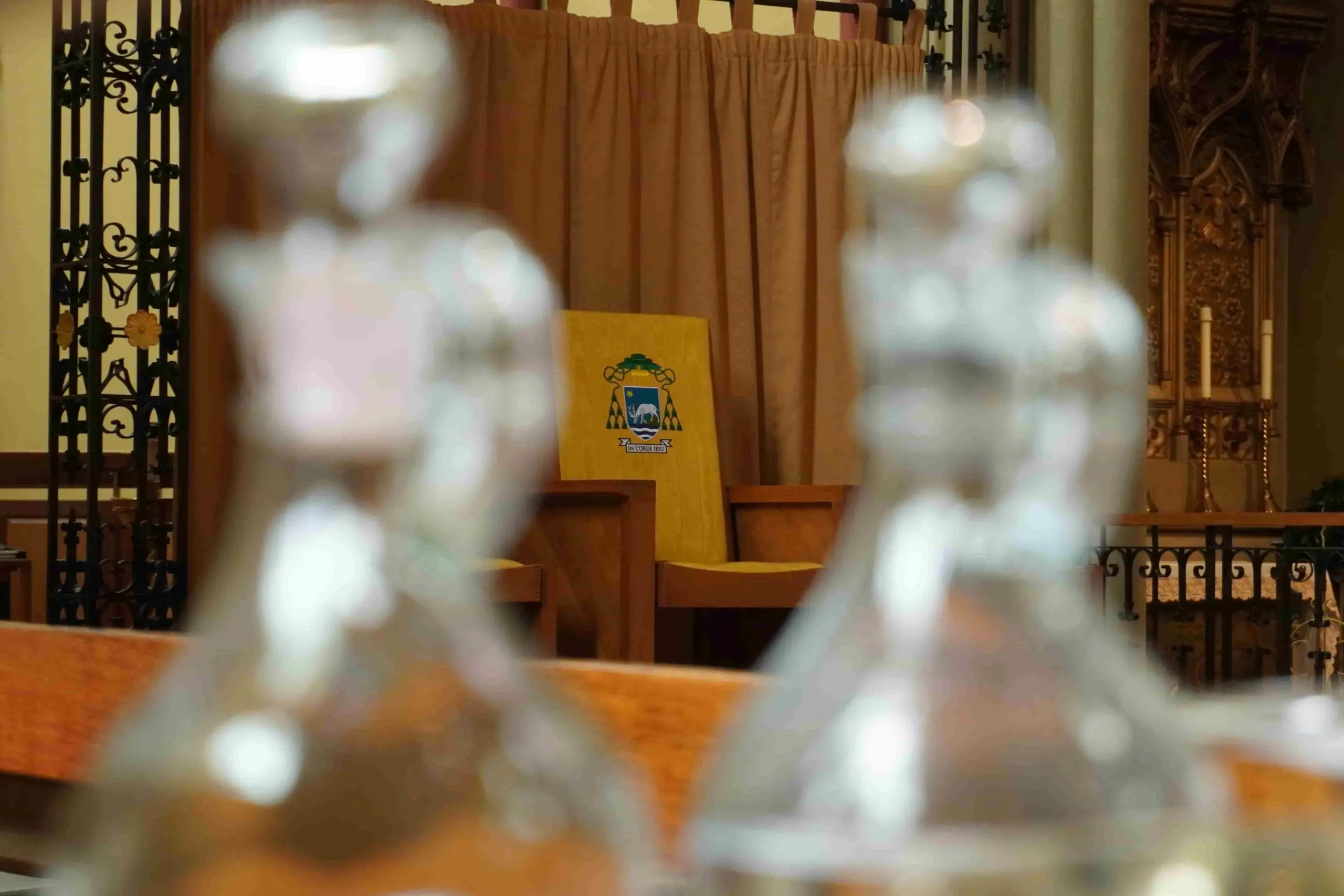 The Bishop of Portsmouth's chair. A yellow chair with the Diocese of Portsmouth crest in the middle of two glass bottles.