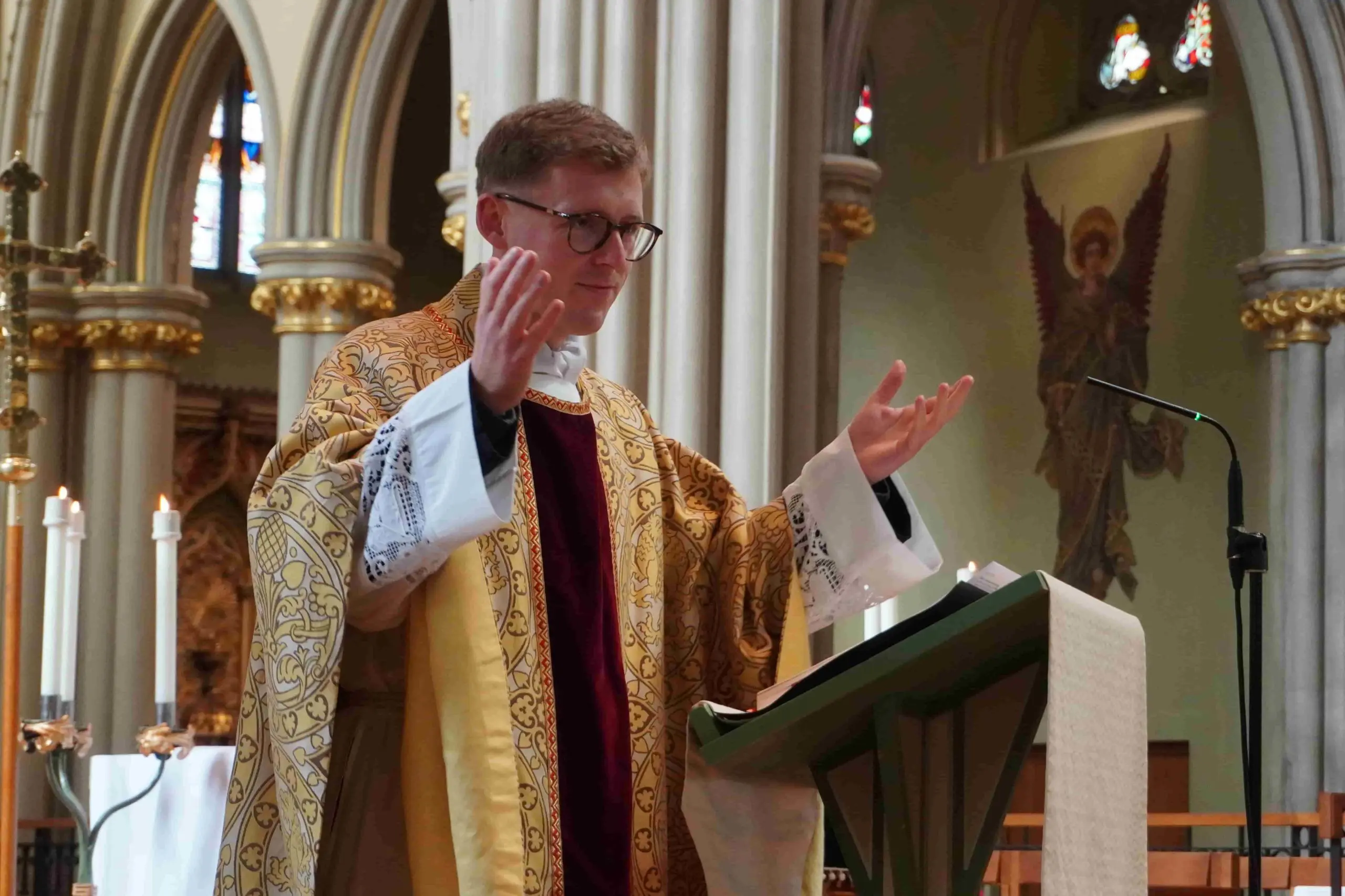 Fr Ryan Browne during mass Fr Ryan Browne wearing priestly clothes and with his hands raised open during mass of the feast of the dedication of St John's Cathedral in 2026